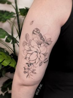 a woman's arm with a bird and flowers tattoo on the left upper arm