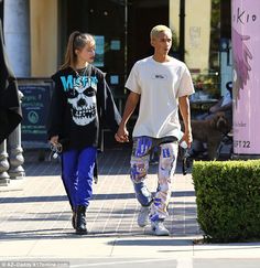 a man and woman walking down the street with skateboards in their hands, both wearing skull t - shirts