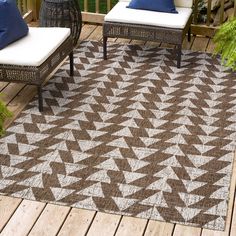 a brown and white rug sitting on top of a wooden deck next to two chairs