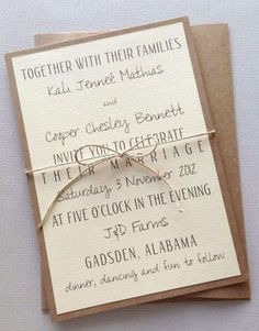 a wedding card with a ring tied to it's front and back, sitting on top of a piece of brown paper