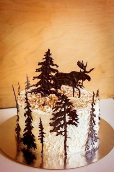 there is a cake with frosting and trees on the top that looks like deer