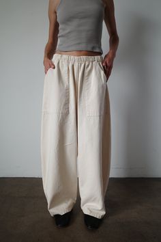 Our take on the everyday pant. Made with an elegantly curved leg, comfortable elastic waist band and large front patch pockets. This pant seamlessly blends comfort and style. An instant classic. Model is 5'6" and wearing the size small. Baggy Bottoms With Elastic Waistband For Everyday, Oversized Solid Ankle-length Bottoms, Oversized Ankle-length Pants, Relaxed Baggy Everyday Bottoms, Relaxed Fit Parachute Pants With Pockets For Loungewear, Comfortable Oversized Solid Bottoms, Comfortable Solid Color Everyday Pants, Loosely Fitted Beige Wide Leg Pants With Side Pockets, Comfortable Everyday Solid Color Pants