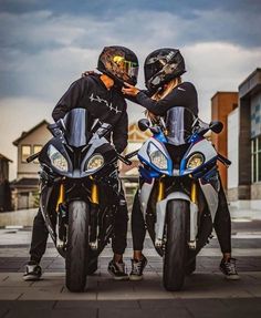 two people sitting on motorcycles with helmets on