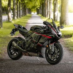 a black motorcycle parked on the side of a road next to some grass and trees