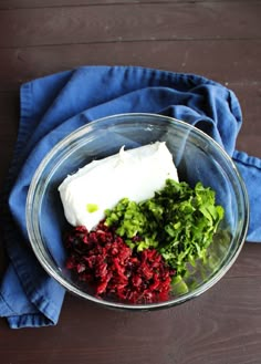 a glass bowl filled with food on top of a blue cloth next to a wooden table