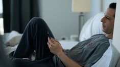 a man laying on the bed looking at his cell phone