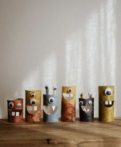 five small paper bags with eyes and mouths on top of a wooden table in front of a white wall