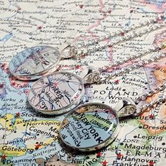 three pocket watches sitting on top of a map with the names of major cities in them