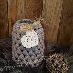 a gray crocheted container with a white heart on it