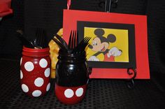 two mason jars are decorated with mickey mouse and polka dot designs, one is holding forks