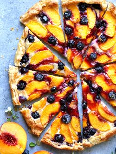 a pie with blueberries and peaches cut into slices on top of a table