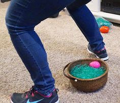 a person standing in front of a basket filled with green grass next to a pink ball