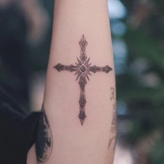 a cross tattoo on the arm of a woman