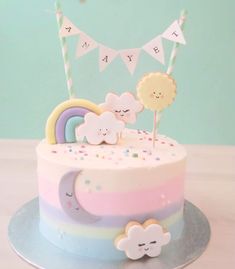 a birthday cake decorated with rainbows and clouds