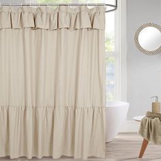 a beige shower curtain with ruffles on the bottom is next to a white bath tub