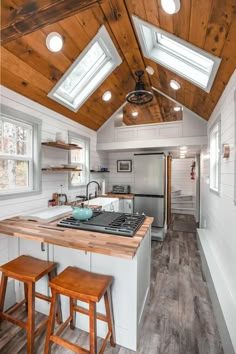 a kitchen with two stools next to an island in the middle of a room