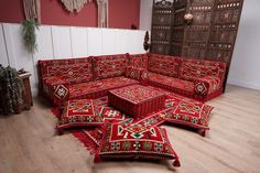 a living room with lots of red couches and rugs on the wooden floor