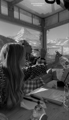 two women sitting at a table in front of a window looking out on the mountains