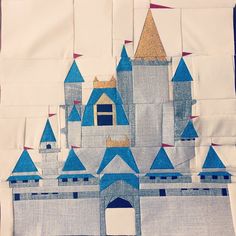 a quilted castle with blue turrets and gold spires is shown on a white piece of cloth