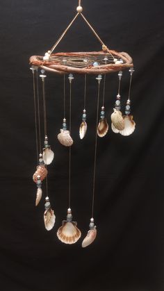 a wind chime with seashells hanging from it's sides on a black background