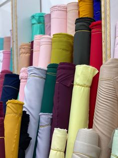 many different colored umbrellas are lined up on the wall in front of each other