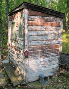 an old outhouse sits in the woods