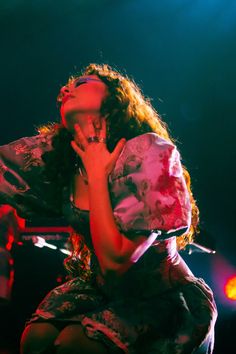 a woman sitting on top of a chair in front of a microphone and holding her hand up to her face