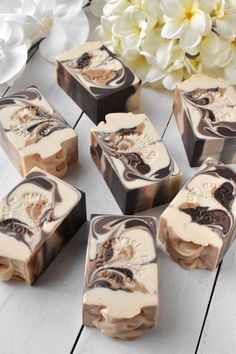 six soap bars sitting on top of a white table next to a bouquet of flowers