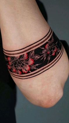 a woman's arm with a tattoo on it and flowers in the band around her wrist