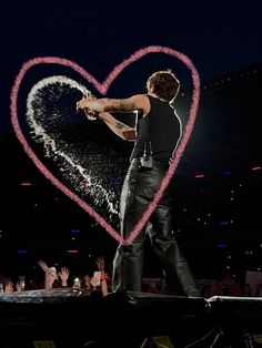 a man standing on top of a stage with a heart drawn in the air above him