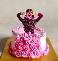 a cake decorated with pink icing and an image of a woman standing on top