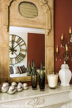 there are many vases on the mantle in front of the mirror and candle holders