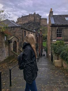 a woman is walking down an alley way with her back turned to the camera,