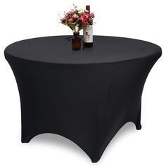 a black table cloth with flowers on it and a bottle of wine next to it