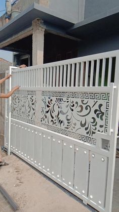 a woman standing in front of a white gate with decorative designs on the top and sides