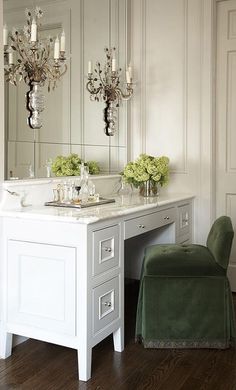 a white vanity with two sinks and green chairs