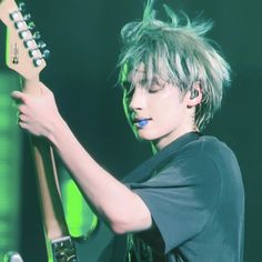 a young man with green hair playing an electric guitar