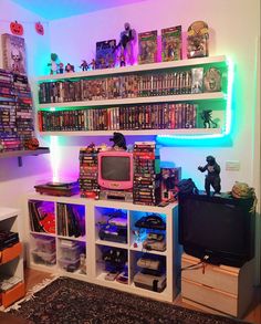 a living room filled with lots of books and movies on shelves next to a tv