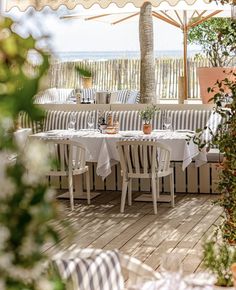 an outdoor dining area with white table cloths and chairs under a canopy over the ocean