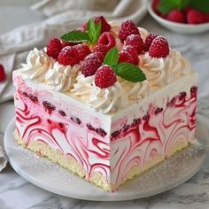 a piece of cake with raspberries and cream frosting on a white plate