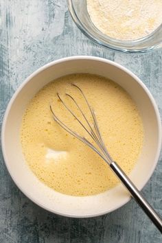 a bowl filled with batter and whisk on top of a blue tablecloth