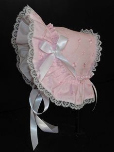 A beautiful Victorian style baby bonnet. Fabric is pink cotton eyelet. Lining is white . Bonnet has an extended back and is trimmed with white lace. Bows and extra long ties are made of white double sided satin ribbon. Size/ Measurement from under ear lobe around top of head to under other ear lobe preemie / 10 inches 0-3 months / 11 inches 3-6 months / 12 inches 6-9 months / 13 inches 9-12 months / 14 inches Bonnet Aesthetic, White Bonnet, Punk Style Outfits, Lace Bonnet, Craft Things, Satin Ribbon Bow, Clothing Reference, Doll Hat, Baby Bonnet