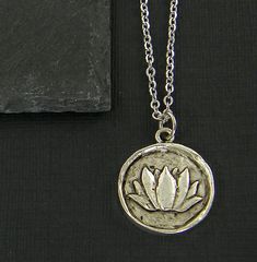 Organic shape silver lotus flower necklace. Lotus blossom is raised and set in a round silver medallion frame. Lotus pendant is made in the USA of .999 fine silver over pewter. Darkening to accent the details. Pendant measurements:     Inches - 15/16 inches tall, 3/4 inches wide     Metric - 23.9 x 19.5 x 3.2mm Silver plated necklace chain - 18 or 24 inches long. ------------------------------ Thank you for visiting! Find more handmade necklaces here - https://www.etsy.com/shop/CharleneSevier?re Sales Copy, Lotus Flower Necklace, Pewter Jewelry, Lotus Pendant, Lotus Blossom, Silver Plated Necklace, Nature Jewelry, Necklace Chain, Flower Necklace