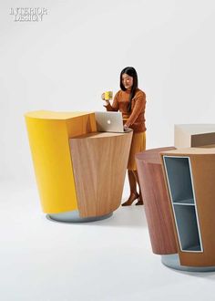 a woman is standing in front of several different colored furniture and she has a laptop on her lap