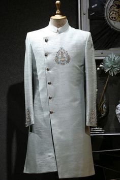 Item contains : Sherwani and Pants  Fabrics : Raw silk  Colours :  Grey Style and Designs : Sherwani has mandarin collar with angrakha (over lapping diagonal button placket) and long sleeves symmetric hem and multiple slits  It's has a beautiful motifs over the left chest embroidered by hands Pants-  Slim fit modern style boot cut pants hook buttons with elastic closure comes with zip and pockets  Size :  Slim fit  Model height is 6 fit and wearing 40 size  Material and Care :  Polyester mix  On Grey Sherwani, Sherwani For Boys, Men Wedding Suit, Groom Sherwani, Grooms Men, Embroidered Sherwani, Sherwani Groom, Mens Kurta Designs, Wedding Sherwani