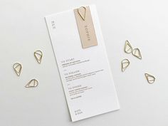 the wedding stationery is laid out next to some gold paperclips on a white table