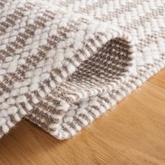 a close up view of a white and brown rug on a wooden floor with wood floors