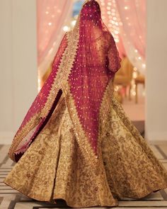 a woman in a red and gold bridal gown is walking down the hall with her back to the camera