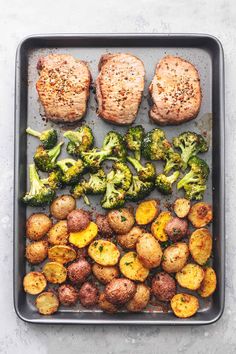 meat, potatoes and broccoli on a baking sheet with seasoning sprinkled