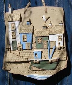 a ceramic wall hanging with a boat and buildings